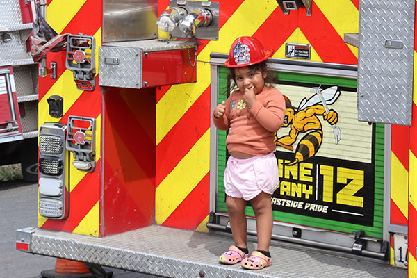 Child standing on rear of firetruck